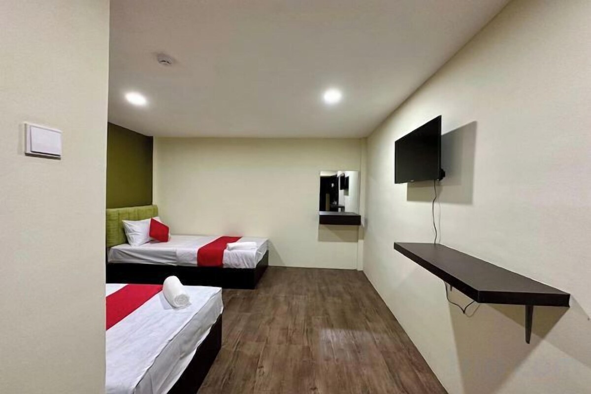 A hotel room with two beds, a TV mounted on the wall, and a wooden floor.