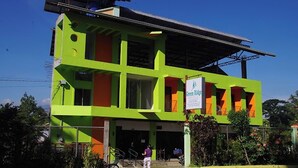 A two-story building with a green and orange facade, a sign reading "Green Ridge," and a covered entrance area. - Green Ridge Apartelle (Malaybalay City)