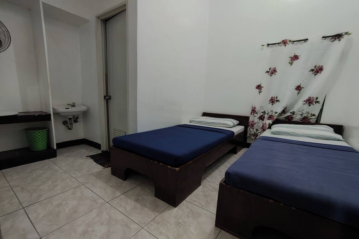 Una habitación con dos camas, un lavamanos y una puerta.
