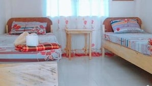 Un dormitorio con dos camas, una mesita y un equipo de aire acondicionado.