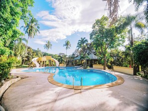 A swimming pool with a curved edge, surrounded by palm trees and a gazebo. - Vista Venice Resort (Morong)