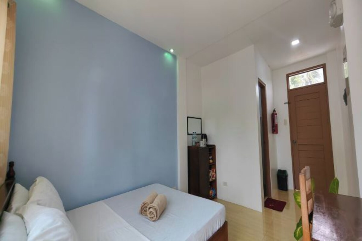 Una habitación con una cama, una mesa de madera, un armario y una puerta.