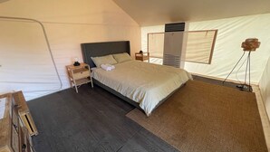 A tented bedroom with a bed, bedside table, lamp, and a view of the outside. - Santillana Hillside Farms (Arayat)