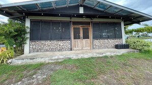A modern house with a large glass window, a wooden door, and a stone wall. - Santillana Hillside Farms (Arayat)