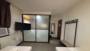 A hotel room with two beds, a TV mounted on the wall, a sliding door, and a coat rack. - Alchan Suites (General Santos)