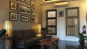 A modern living room with a sofa, two lamps, a coffee table, and framed pictures on the wall. - Alchan Suites (General Santos)