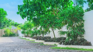 A pathway lined with plants and a white wall. - Alchan Suites (General Santos)