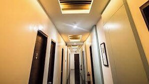 A hotel hallway with a modern ceiling design, doors on both sides, and a central staircase. - Alchan Suites (General Santos)