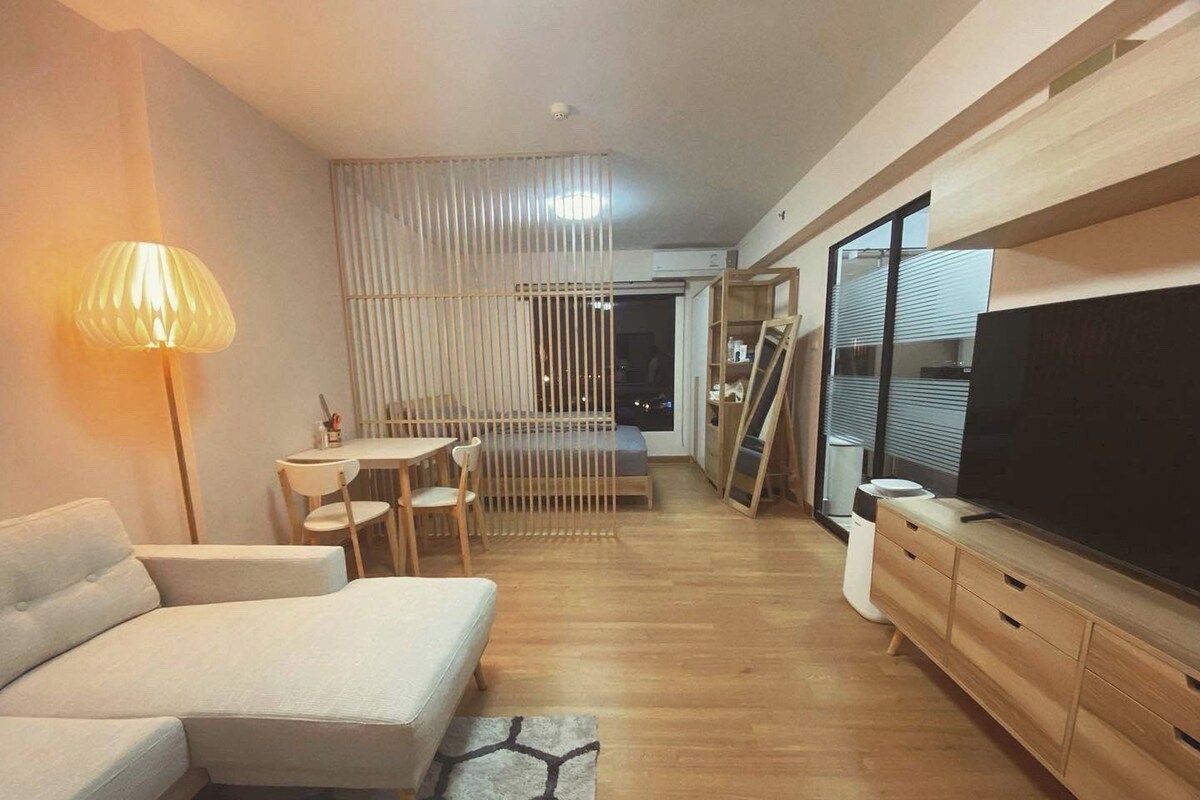 A modern living room with a sofa, a dining table, and a TV.