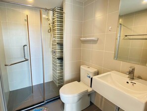 A modern bathroom with a glass shower enclosure, a toilet, and a sink with a mirror above it. - Vista Old Town Phuket (Phuket)