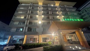 Un hotel de varios pisos con una entrada destacada y un cartel que dice 'CARPEDIEM'.
