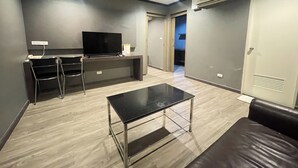 Una sala de estar moderna con una televisión de pantalla plana, una mesa de centro, un sofá y un escritorio con una silla.
