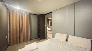 Habitación de hotel con cama, cortinas, armario y baño visible a través de una puerta abierta.