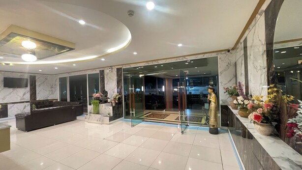 Un vestíbulo amplio con mostrador de recepción, zona de estar y entrada de cristal que da al comedor.
