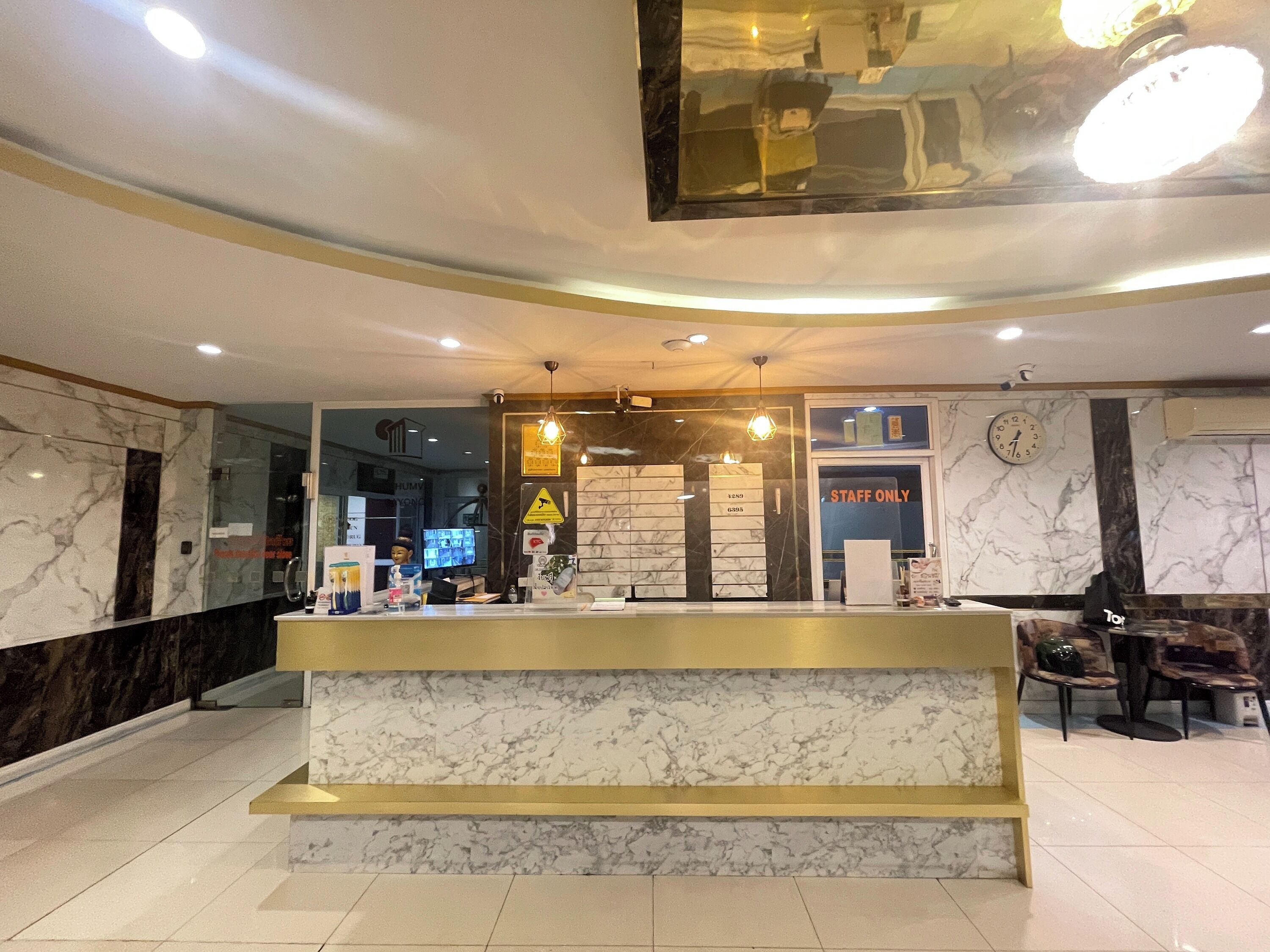 Un'area reception di un hotel con un banco in marmo, una sveglia e un cartello con la scritta 'PERSONALE SOLO'.