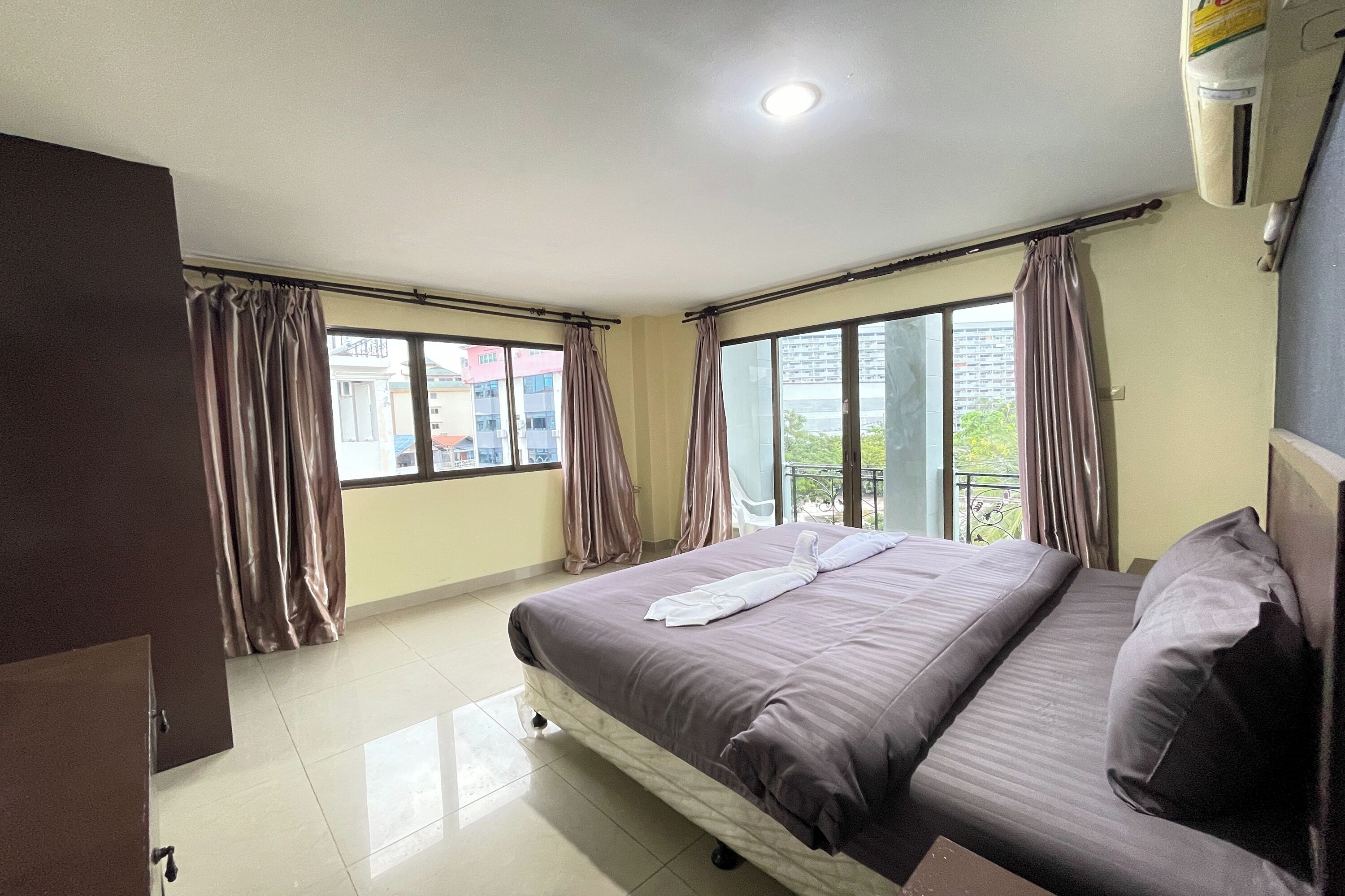 A hotel room with a bed, curtains, a window, and a balcony.
