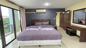 Een slaapkamer met een groot bed, nachtkastje, kast, spiegel en uitzicht op een balkon.