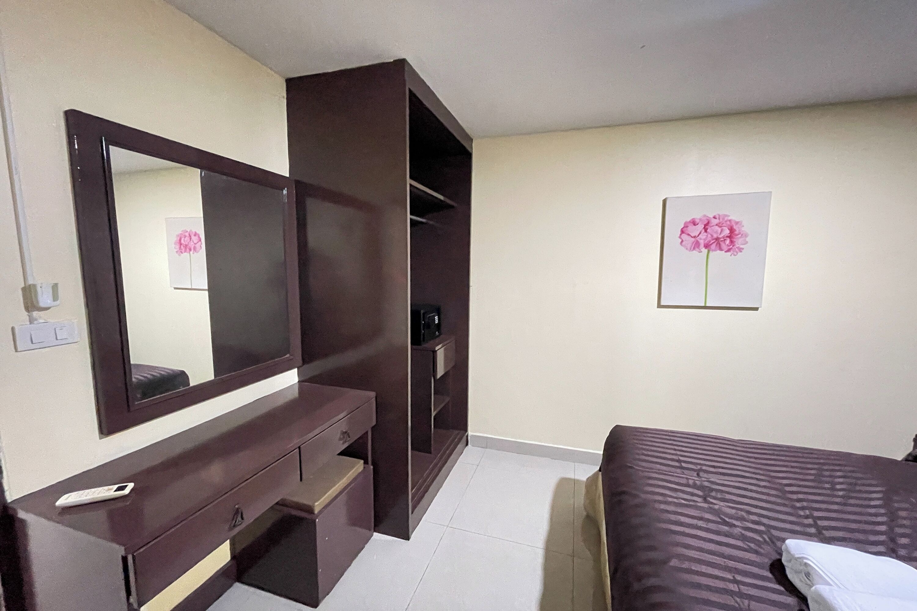 Um quarto com cama, cômoda, espelho, guarda-roupa e um quadro na parede.