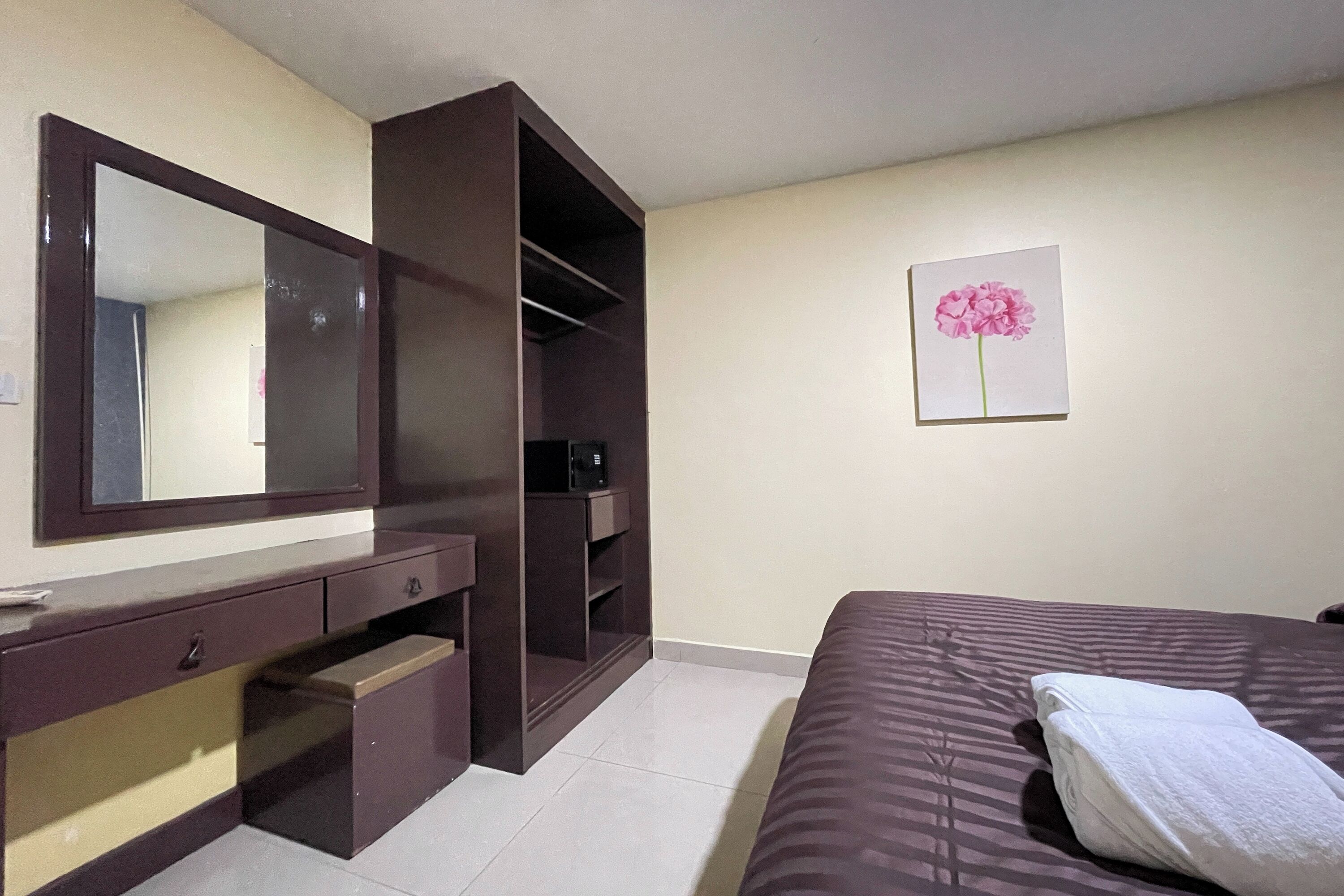 Un dormitorio con cama, armario, espejo y un cuadro en la pared.