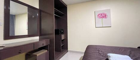 Un dormitorio con cama, armario, espejo y un cuadro en la pared.