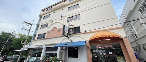 Un edificio con un cartel que dice "ROOM RENT", toldo azul y motocicletas estacionadas afuera.