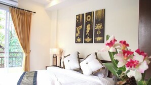 A hotel room with a bed, a nightstand, a lamp, and a window with curtains. There are three wall-mounted paintings above the bed. - Le Viengping Chiangmai (Chiang Mai)
