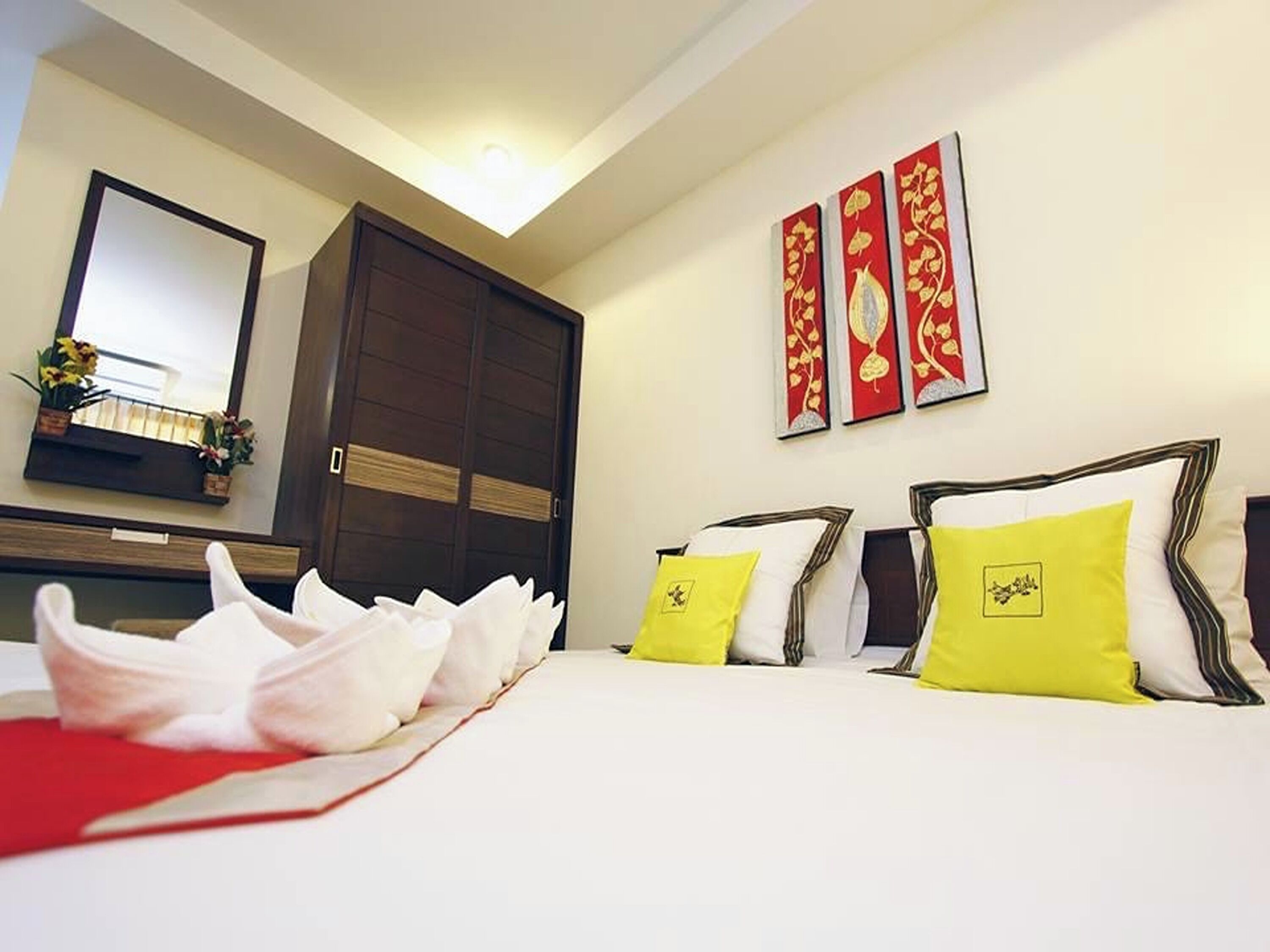 Una habitación de hotel con cama, armario, espejo y decoración en la pared.