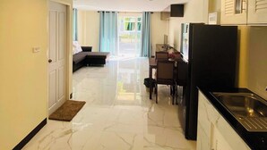 A modern kitchen with a black refrigerator, a dining area with a table and chairs, and a living room with a sofa and a window with curtains. - Le Viengping Chiangmai (Chiang Mai)