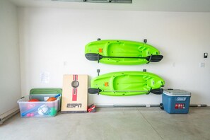 Un garaje con dos kayaks colgados en la pared, un baúl y un enfriador.