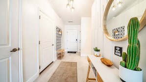 A hallway with white doors, a wooden bench, a cacti planter, and a WiFi sign.
