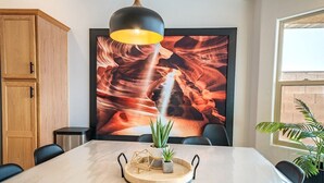 A conference room with a marble table, a large painting of red rock formations, a potted plant, and a pendant light.