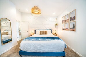 A modern bedroom with a large bed, a hanging light fixture, and framed pictures on the wall. - Stonecliff Escape Sum (Page)