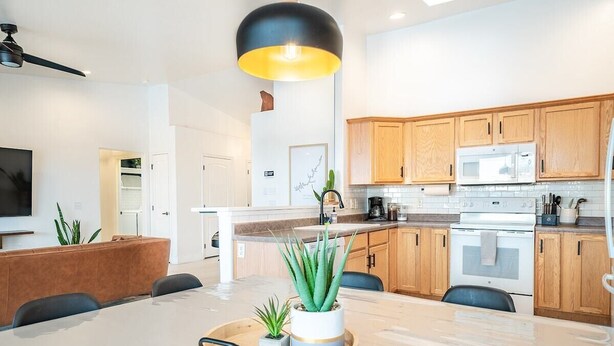 A modern kitchen with wooden cabinets, a white stove, and a dining area with a table and chairs.