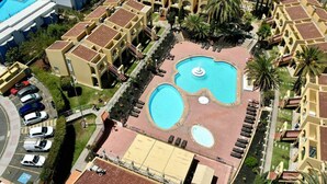 Un hotel con varias edificaciones, una piscina central y un estacionamiento.