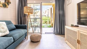 Una sala de estar moderna con un sofá, una lámpara de pie y un reposapiés de ratán.