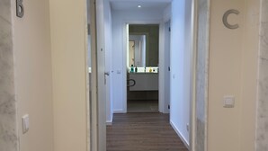 A hallway with a wooden floor, white walls, and a marble threshold. Letters B and C are visible on the walls. - Lovely Studio (Faro)