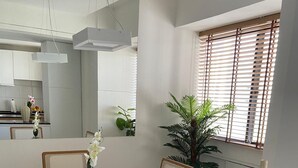 A modern kitchen with white cabinets, a round dining table, and a potted plant.