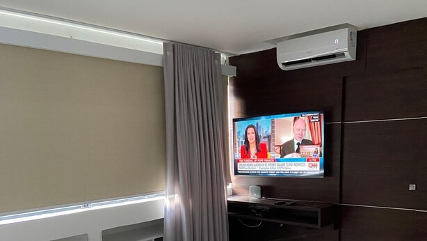 A modern living room with a flat-screen TV, grey sofa, and a coffee table.