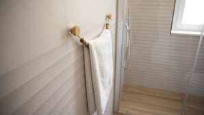 A bathroom with a towel rack, a shower, and a window. - BEIGE APARTAMENT (Gragnano)