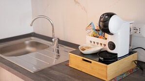 A kitchen with a modern sink, a coffee maker, and a wooden box containing snacks. - BEIGE APARTAMENT (Gragnano)