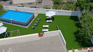 An aerial view of a rooftop with a swimming pool, green lawn, and lounge chairs. - BEIGE APARTAMENT (Gragnano)