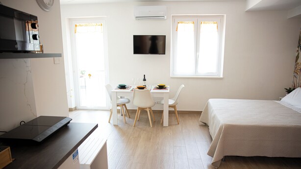 A modern bedroom with a bed, a desk with a computer, and a TV. - BEIGE APARTAMENT (Gragnano)