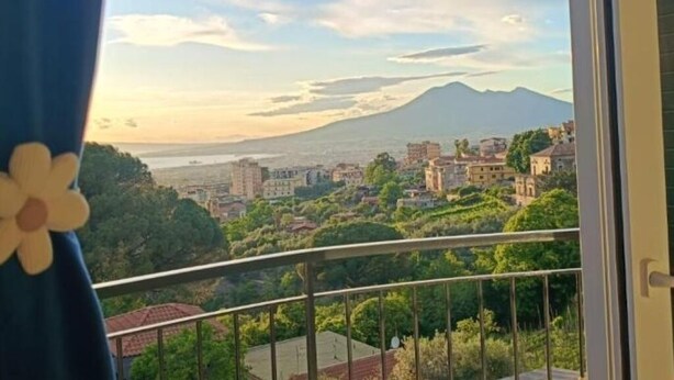 Varanda com vista para uma paisagem urbana e montanha.