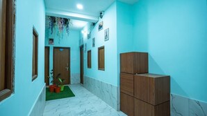 Un pasillo con piso de mármol, puertas de madera y alfombra verde.