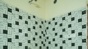 Un baño con pared de azulejos, cabezal de ducha, inodoro y lavabo.
