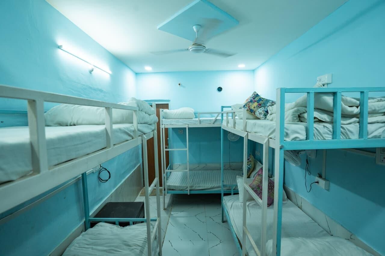 Un dormitorio con literas, ventilador de techo y ventana pequeña.