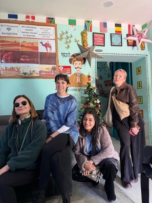 Un grupo de personas en una habitación con una pared decorada que incluye banderas, un árbol de Navidad y varios letreros.