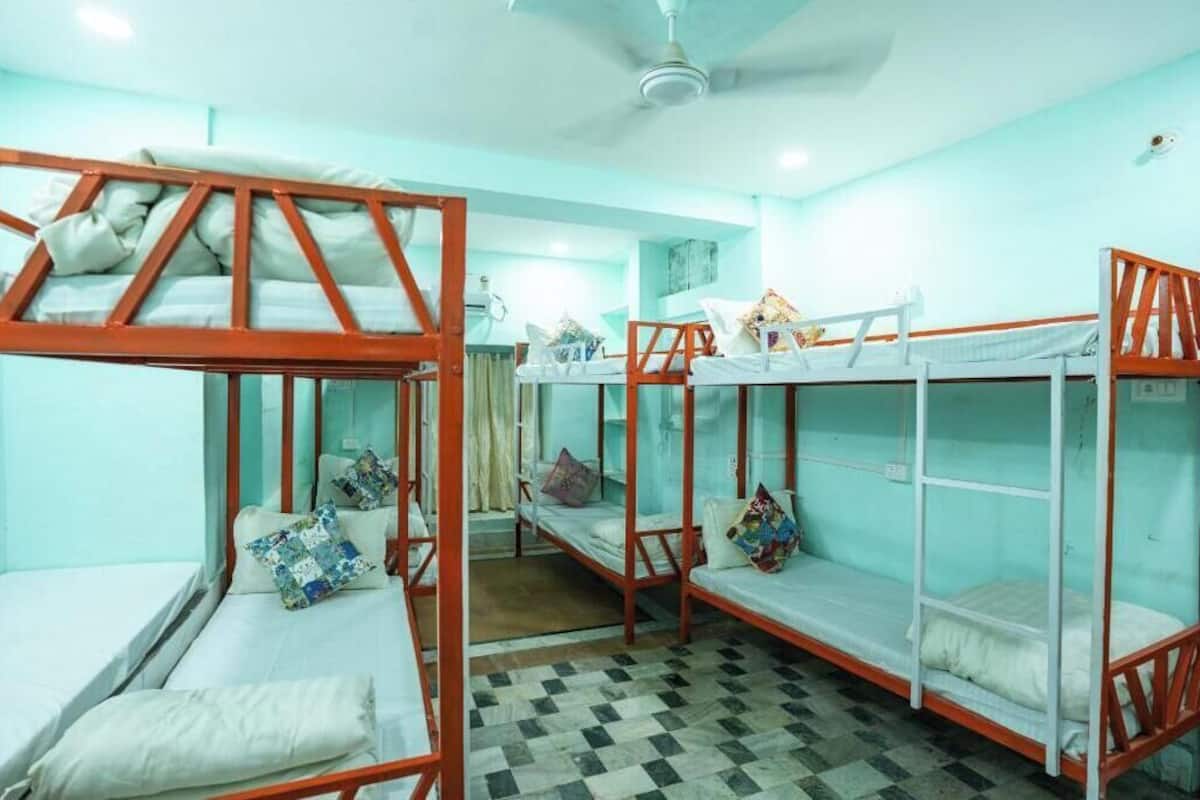 A dormitory room with bunk beds, a checkered floor, and a ceiling fan.