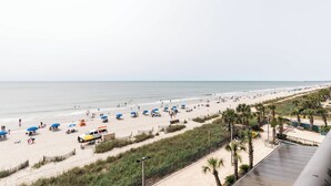 A beach with umbrellas, a sandy path, and a view of the ocean. - Sky-High Oceanfront Stay Pools and DJs & More (Myrtle Beach)
