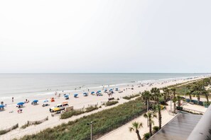 A beach with umbrellas, a sandy path, and a view of the ocean.